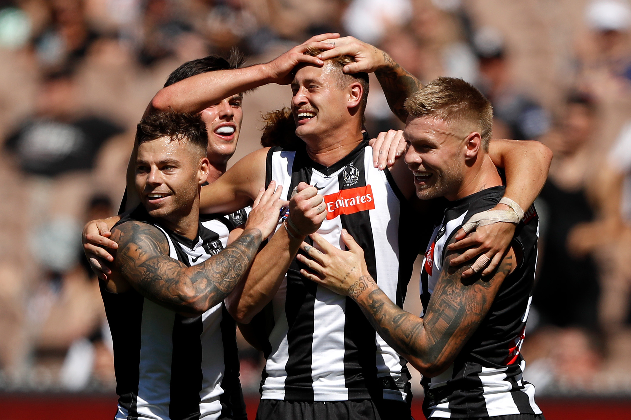 A group of Collingwood players gather around Nathan Krueger and pat him on the head