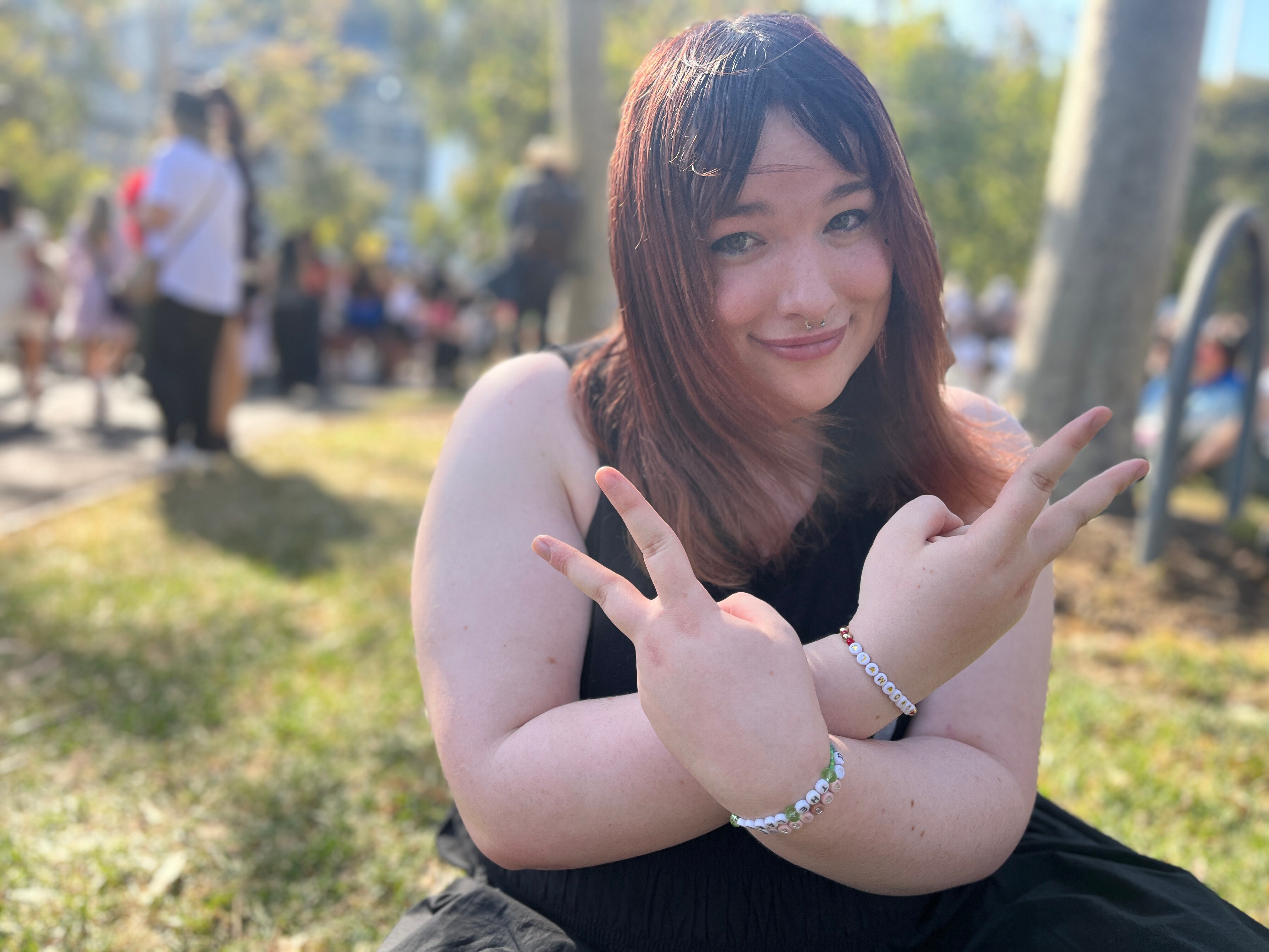 Trans woman with Taylor Swift bracelets doing the peace symbol with her hands.