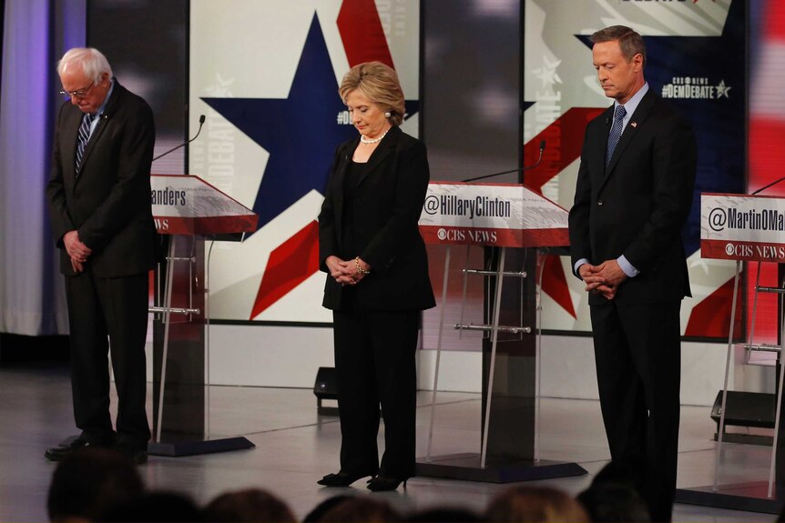 Democratic US presidential candidates bow their heads in a moment of silence for the victims of Paris attacks