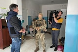 Cameraman filming man in bullet proof vest and soldier in uniform and balaclava.