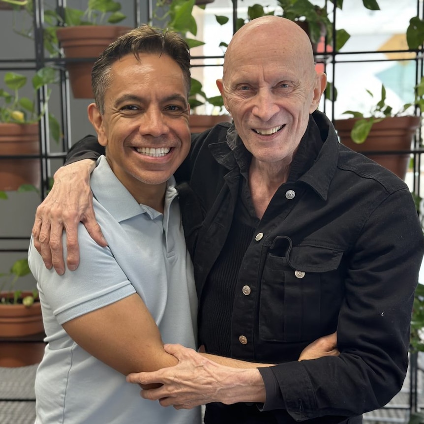 David Bedella and Richard O'Brien pose for a photo with the arms wrapped around each other smiling