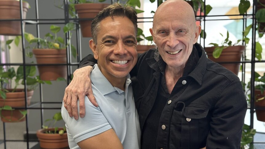 David Bedella and Richard O'Brien pose for a photo with the arms wrapped around each other smiling