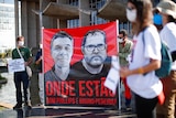 Protesters hold up large sign featuring images of two missing men in Brazil.