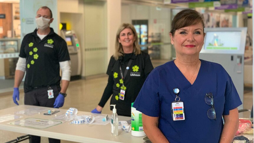 Suzi Hannan in nurses uniform standing in front a desk in a building atrium used for testing for coronavirus