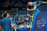 A tennis umpire leans down and wags his finger at a player he is arguing with during a match.