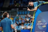 A tennis umpire leans down and wags his finger at a player he is arguing with during a match.