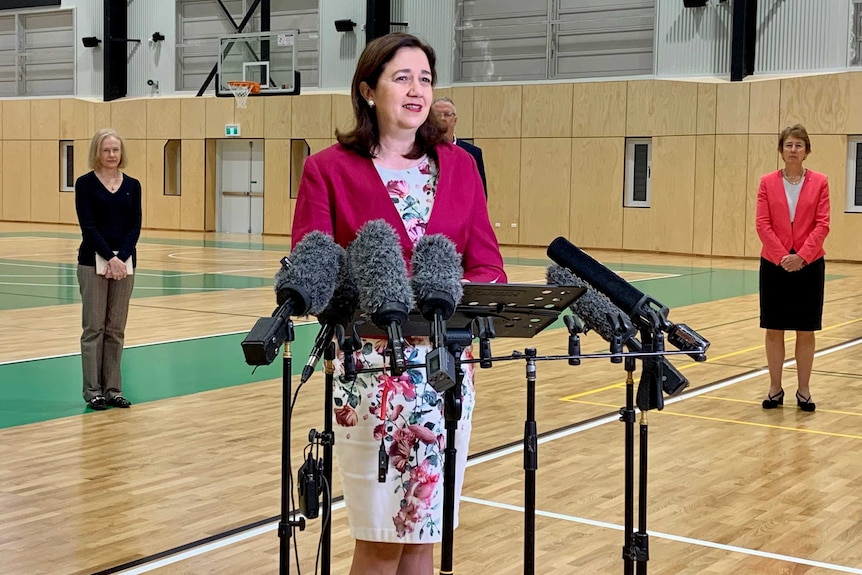 Queensland Premier Annastacia Palaszczuk stands in front of microphones
