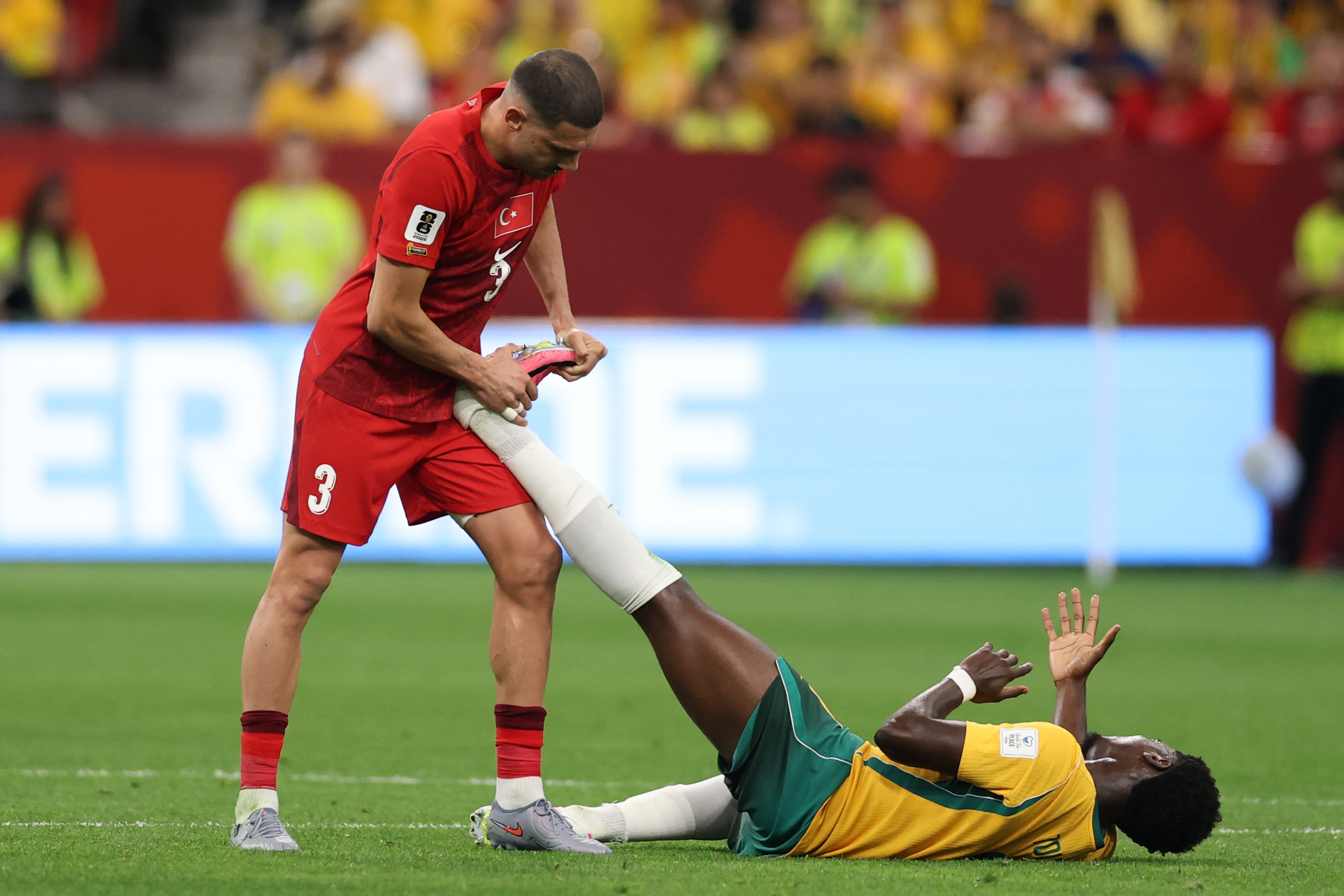 Merih Demiral of Turkiye helps Mohamed Toure of Australia stretching his leg