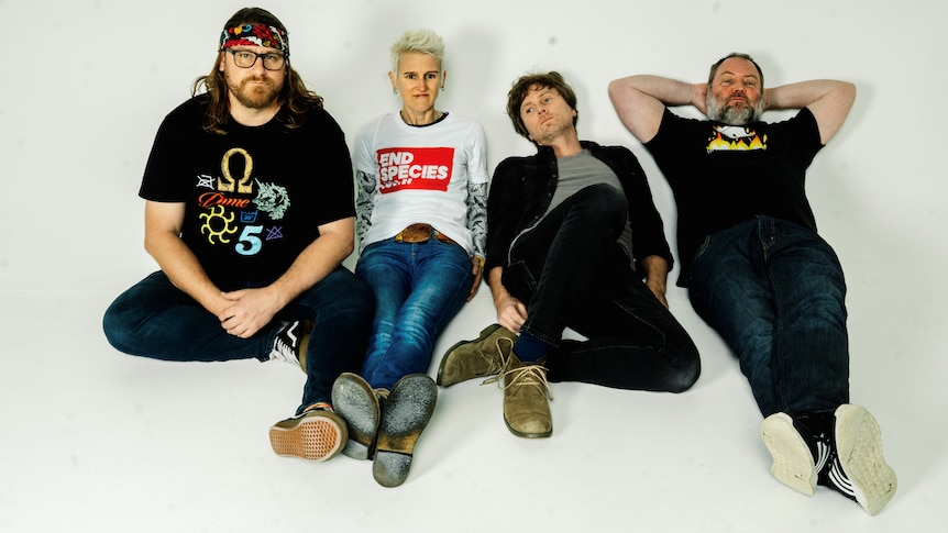 The four members of Jebediah lie and pose on the floor of a white photo stage