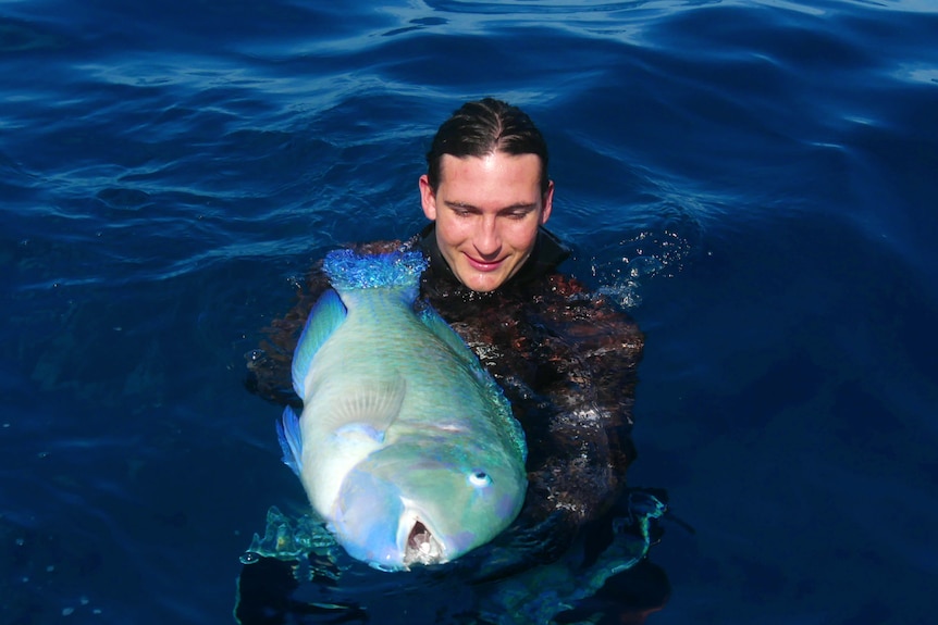 A man in the water holds a large fish