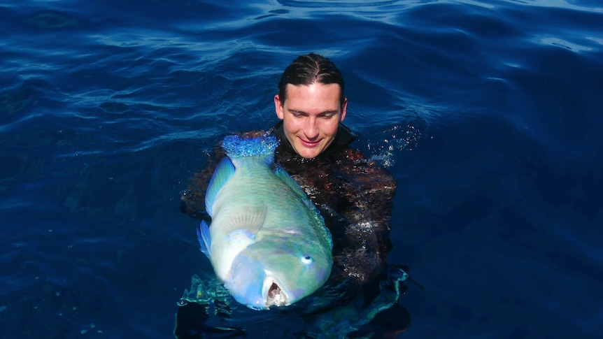 A man in the water holds a large fish