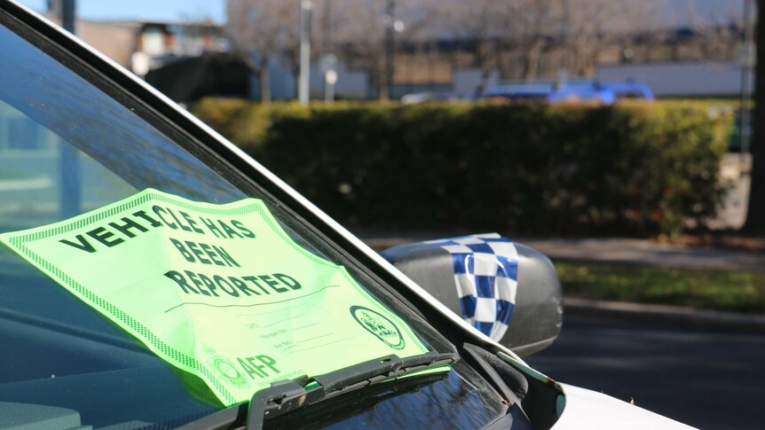 Police tape and a ACT government notification sign on a dumped car in Belconnen.