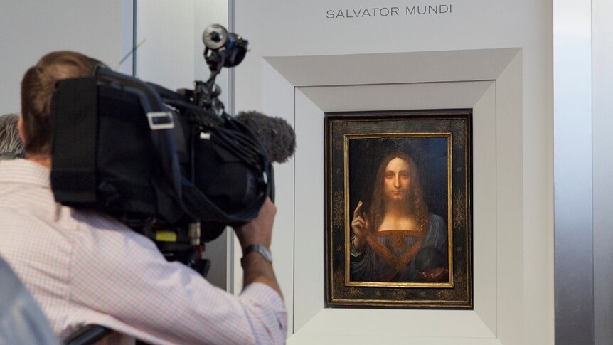 A cameraman films Leonardo da Vinci's painting Salvator Mundi.