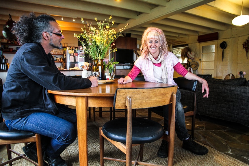 A man and woman sit at a kitchen table.