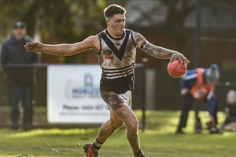 AFL player in the action of kicking a ball during a match