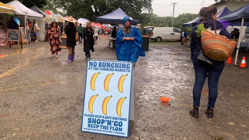 Farmers markets scene with sign saying 'no bunching' to promote social distancing during COVID-19.