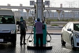 A man fills up a car at a petrol station