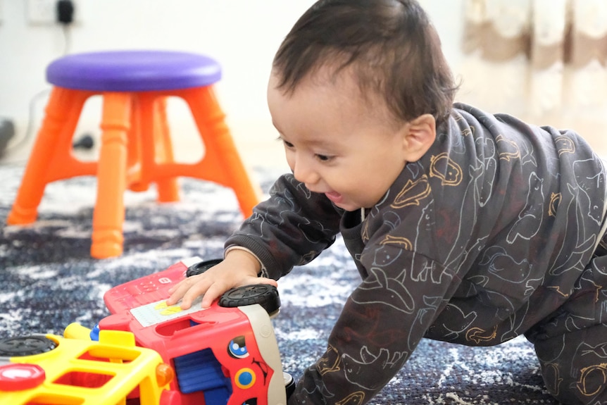 A baby playing with a truck. 