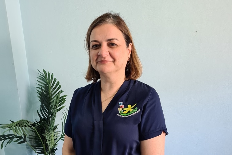 Grace Fava stands facing the camera in room with her organisation uniform on 