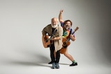 Jack Black and Kyle Gass of Tenacious D play guitars. Black holds up the devil horns sign with his fingers.