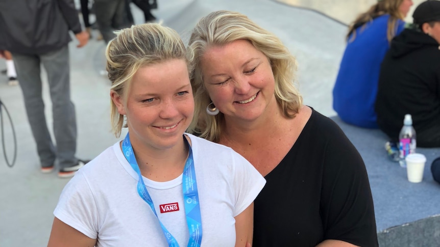 Exterior beside a skate bowl Poppy showing a medal hugged by her mum Thomas