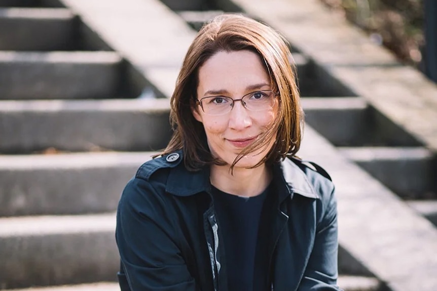 Doris Reisinger, a woman with short brown hair wearing a dark jacket, poses for a photo on some concrete stairs