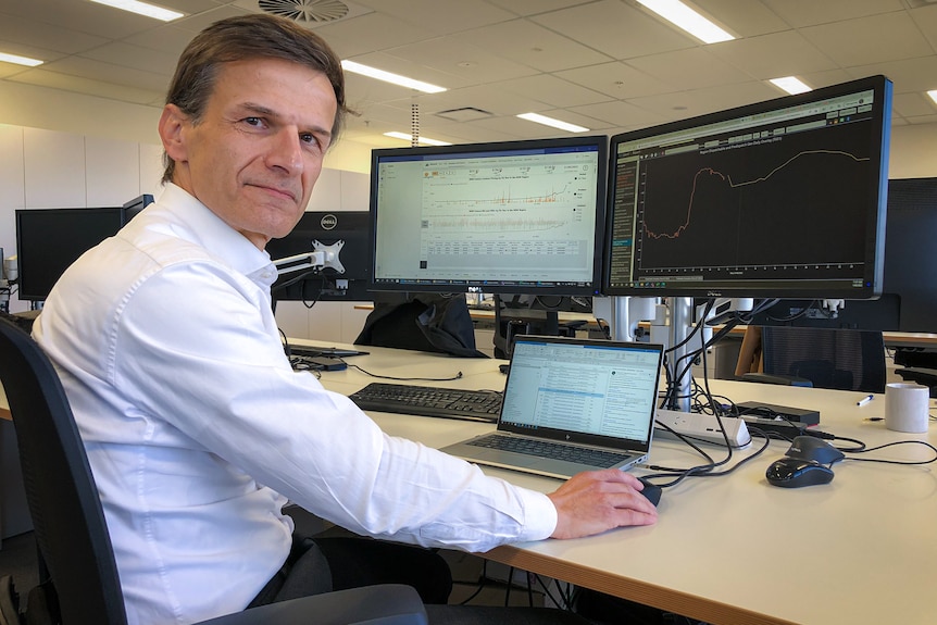 A man sits in front of a few computer screens.