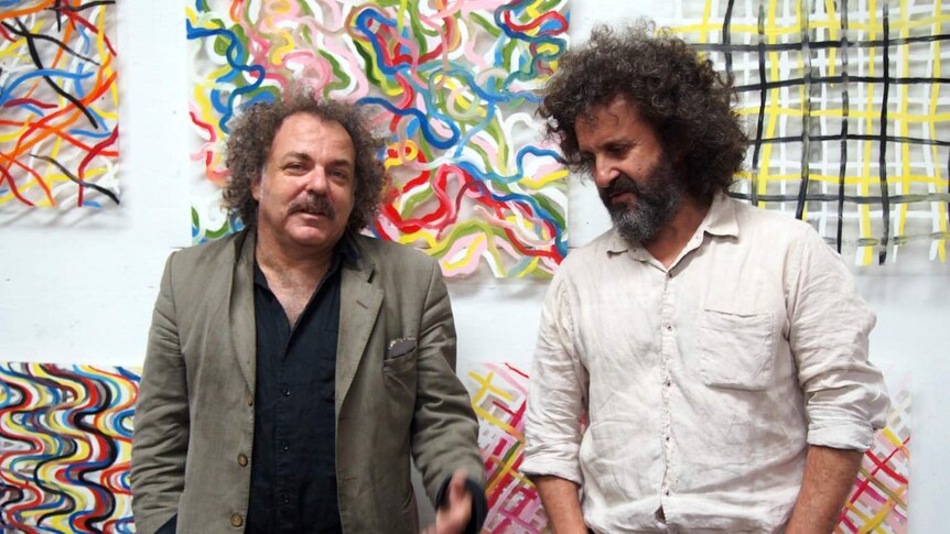 George Xylouris and Jim White stand together in front of some paintings.