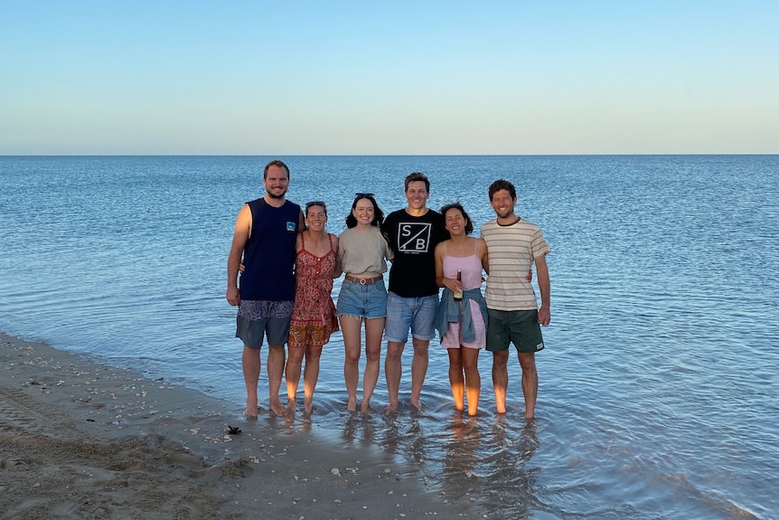 Image of people standing in shallow water at a beach