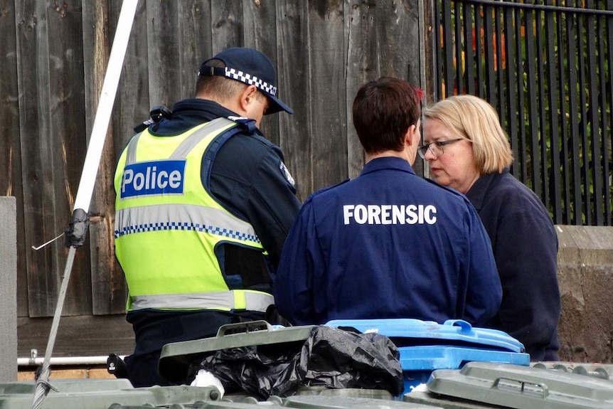 A policeman and forensic officer speak to a woman at the scene of a siege in Brighton at serviced apartments.