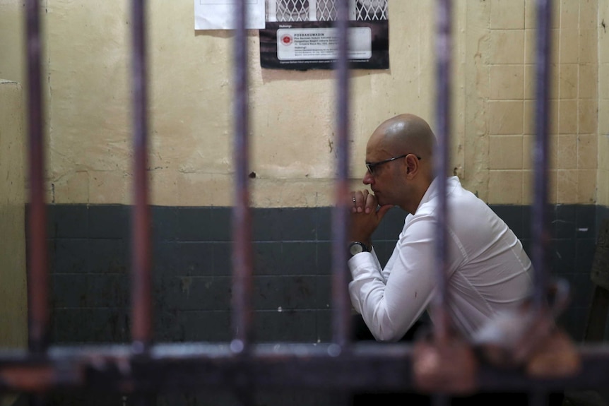 Canadian teacher Neil Bantleman sits with his hands clasped in a holding cell in Jakarta.