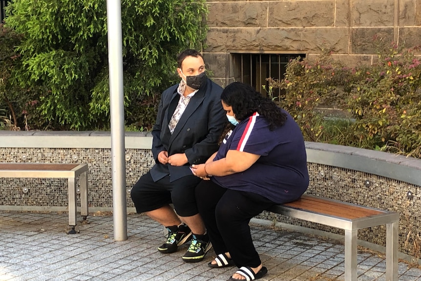 A man and a woman sit on a bench.