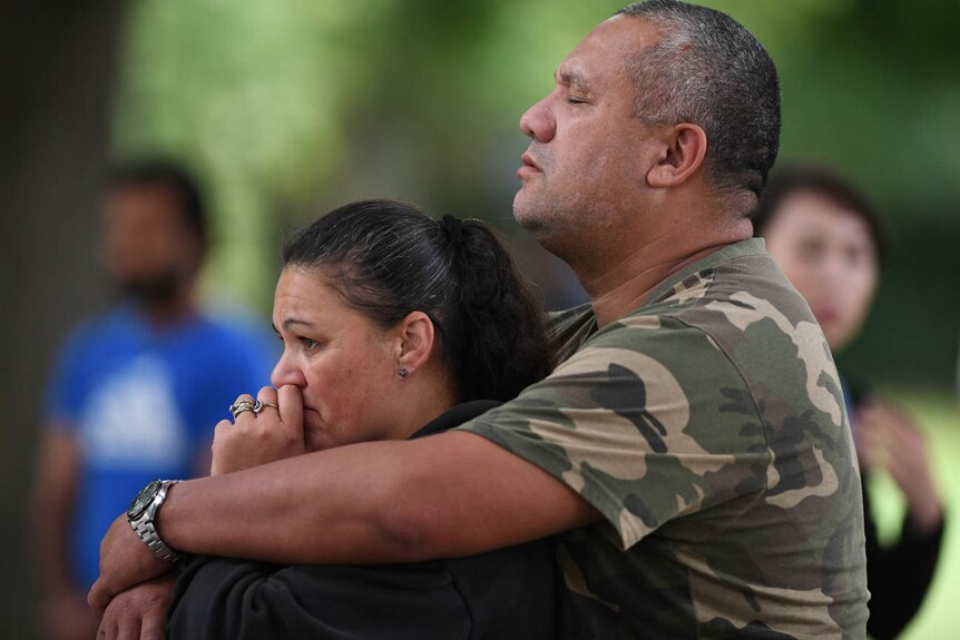 A man holds a woman as they mourn on Dean's Avenue in Christchurch, New Zealand.