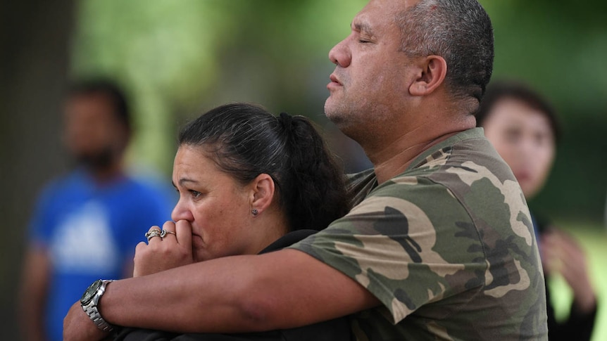 A man holds a woman as they mourn on Dean's Avenue in Christchurch, New Zealand.