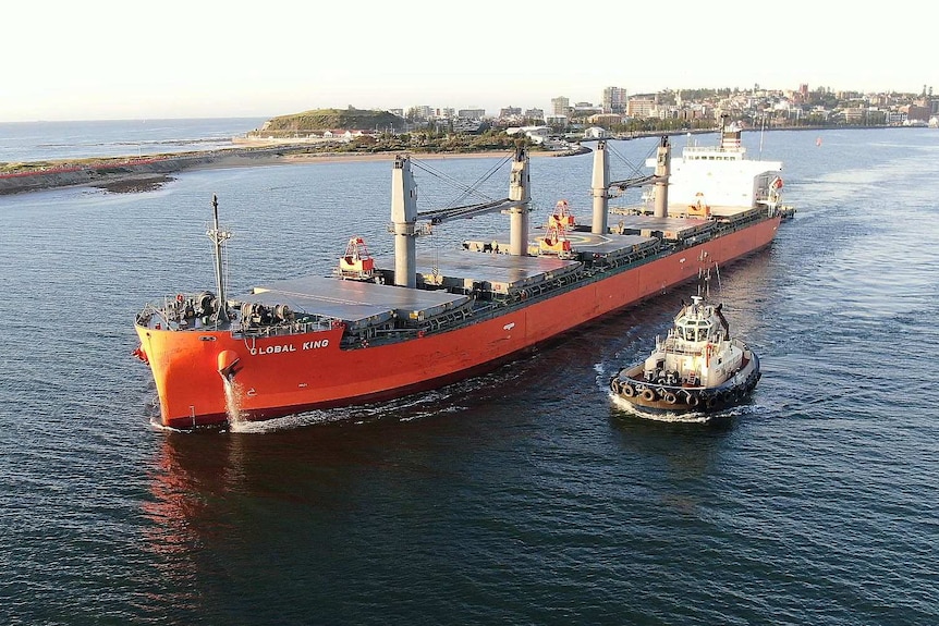 An aerial view of a large ship leaving port.