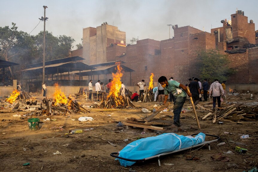 Man prepares a funeral pyre in India