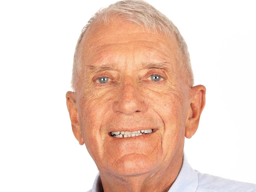An older man with grey hair smiles at the camera.