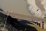 A bridge above water with sludge on it.
