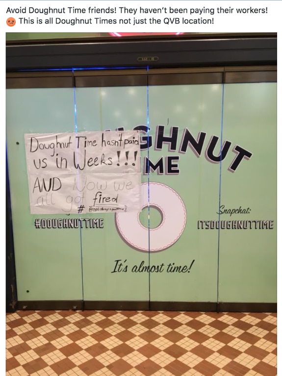 A paper sign stuck on a Doughnut Time store front says "Doughnut Time hasn't paid us in weeks and now we all got fired.