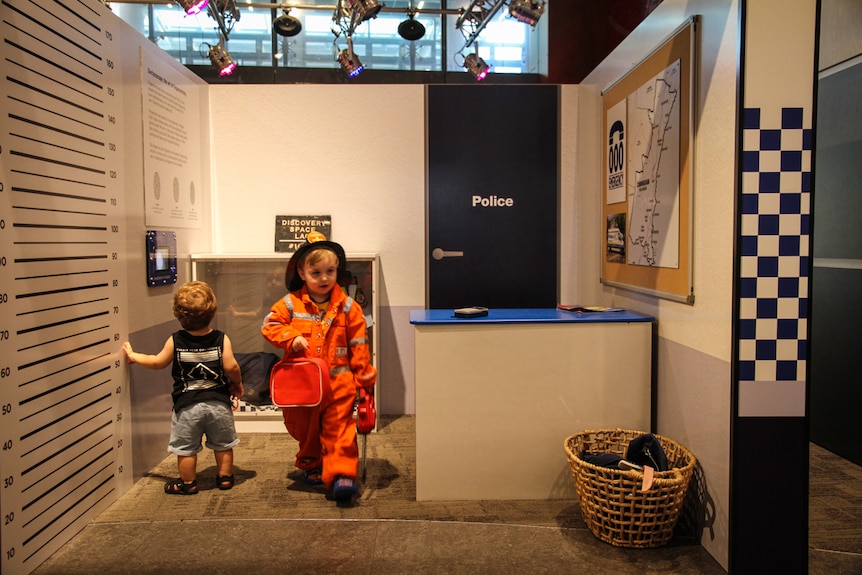 A small child and another older child dressed up as a firefighter