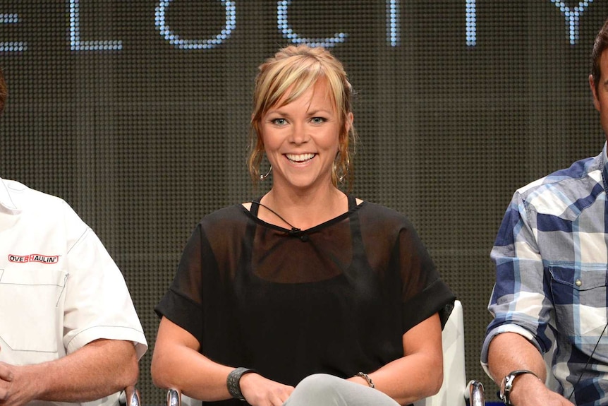 Jessi Combs smiles as she sits between Chip Foose and Chris Jacobs at a panel discussion