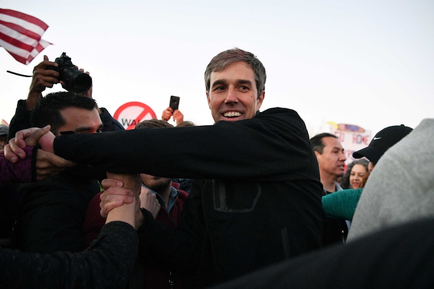 Beto O'Rourke shakes hands in a crowd of people.