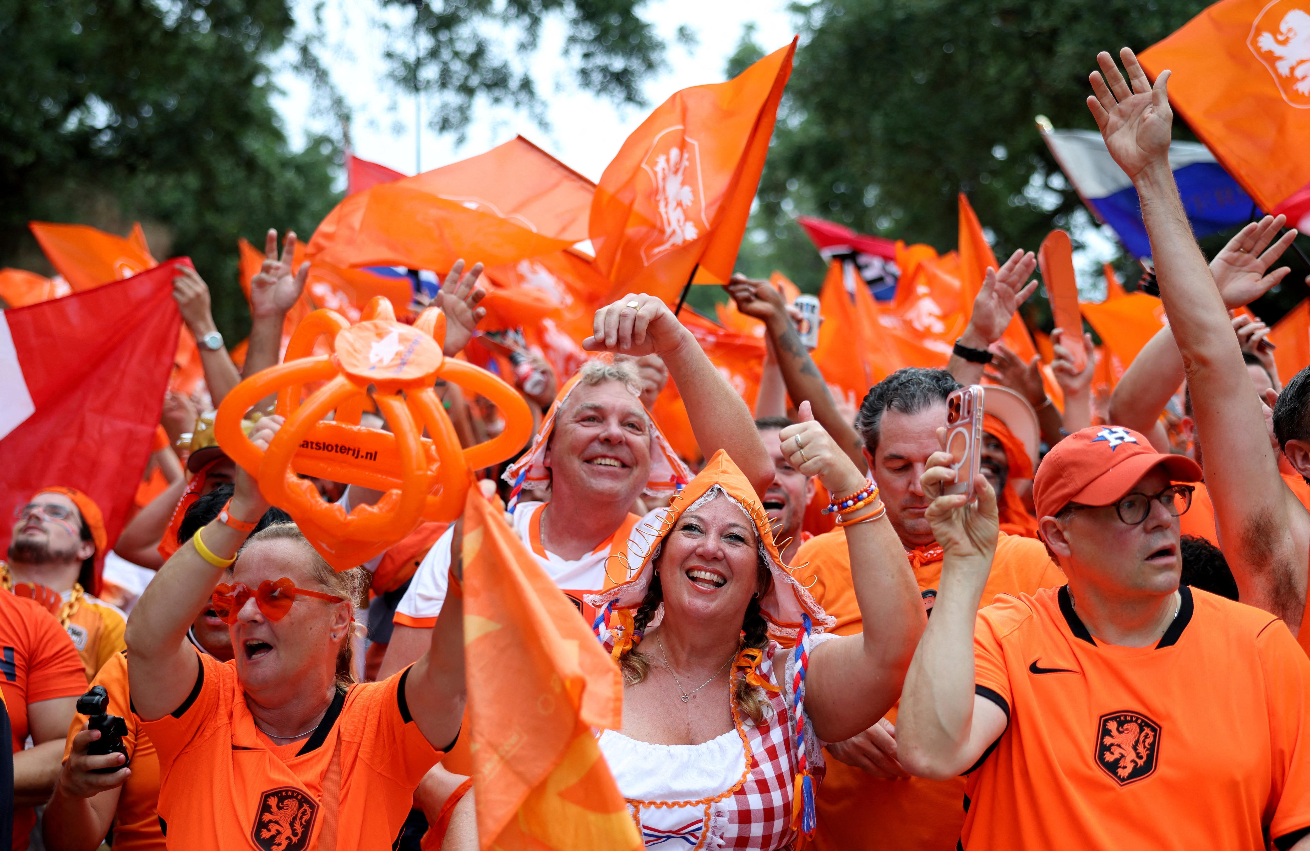 A close up of Netherlands fans dressed in orange smiling
