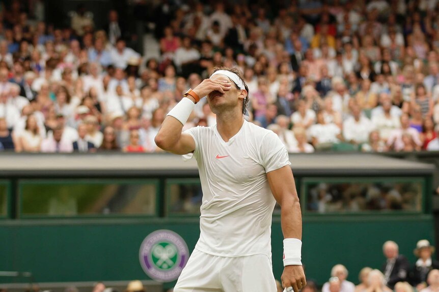 Rafael Nadal holds his hand to his face after losing a point