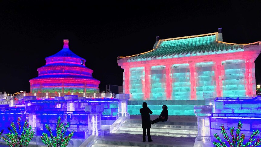 An ice replica of Beijing's Temple of Heaven is lit up in different colours at night.