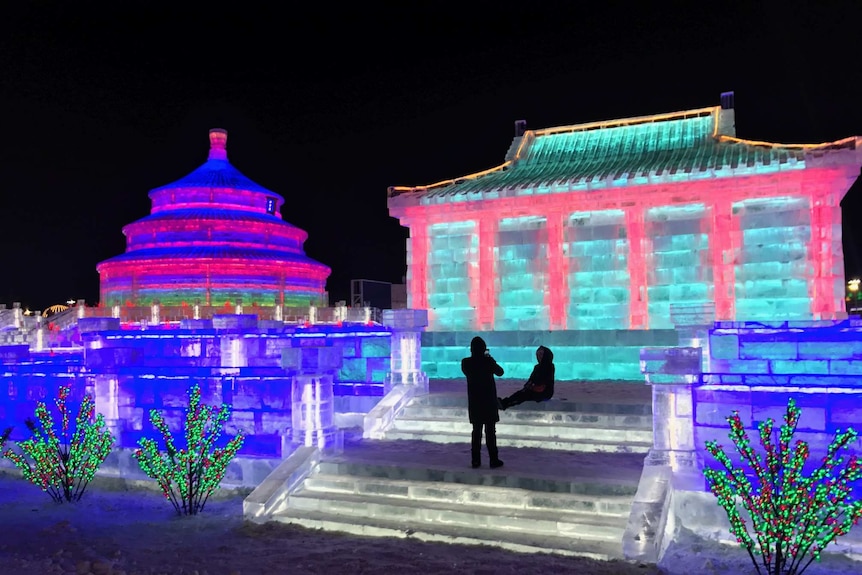 An ice replica of Beijing's Temple of Heaven is lit up in different colours at night.