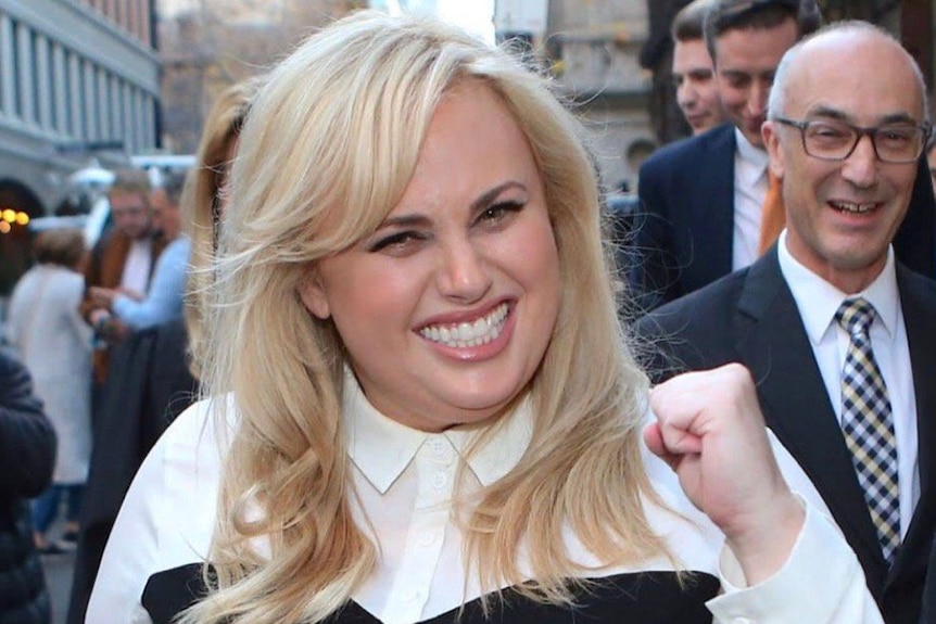 Actress Rebel Wilson pumps her fist in celebration outside court after winning her defamation case.