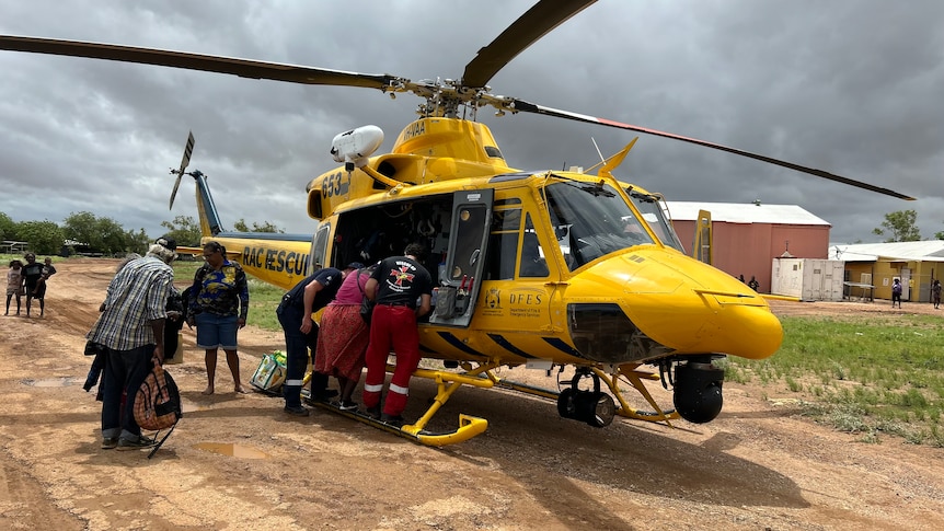 Noonkanbah residents are ushered on to a rescue helicopter by emergency workers.