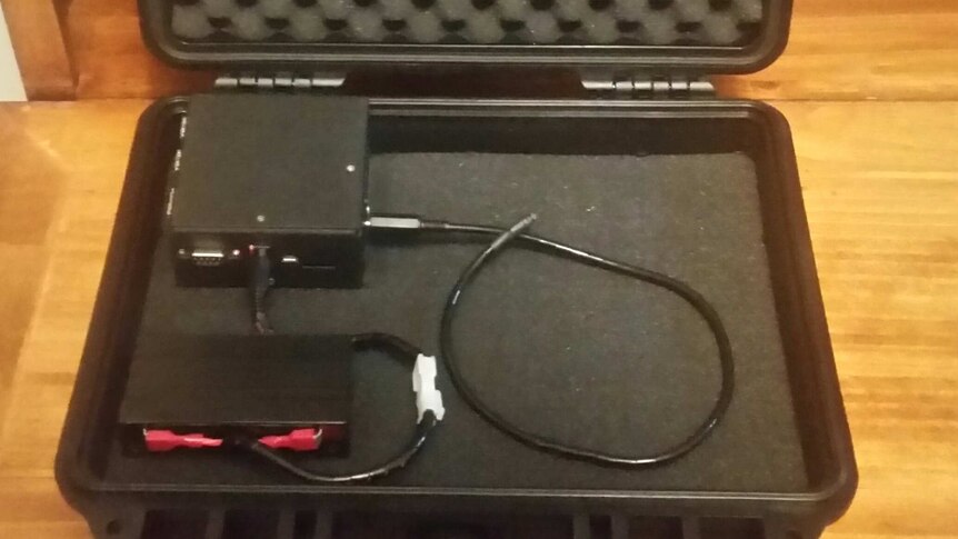 A small recording device lying in a padded case.
