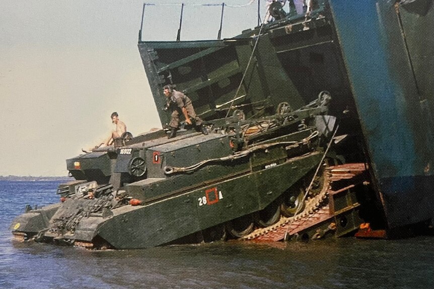 A tank rolls out of a big ship into shallow water